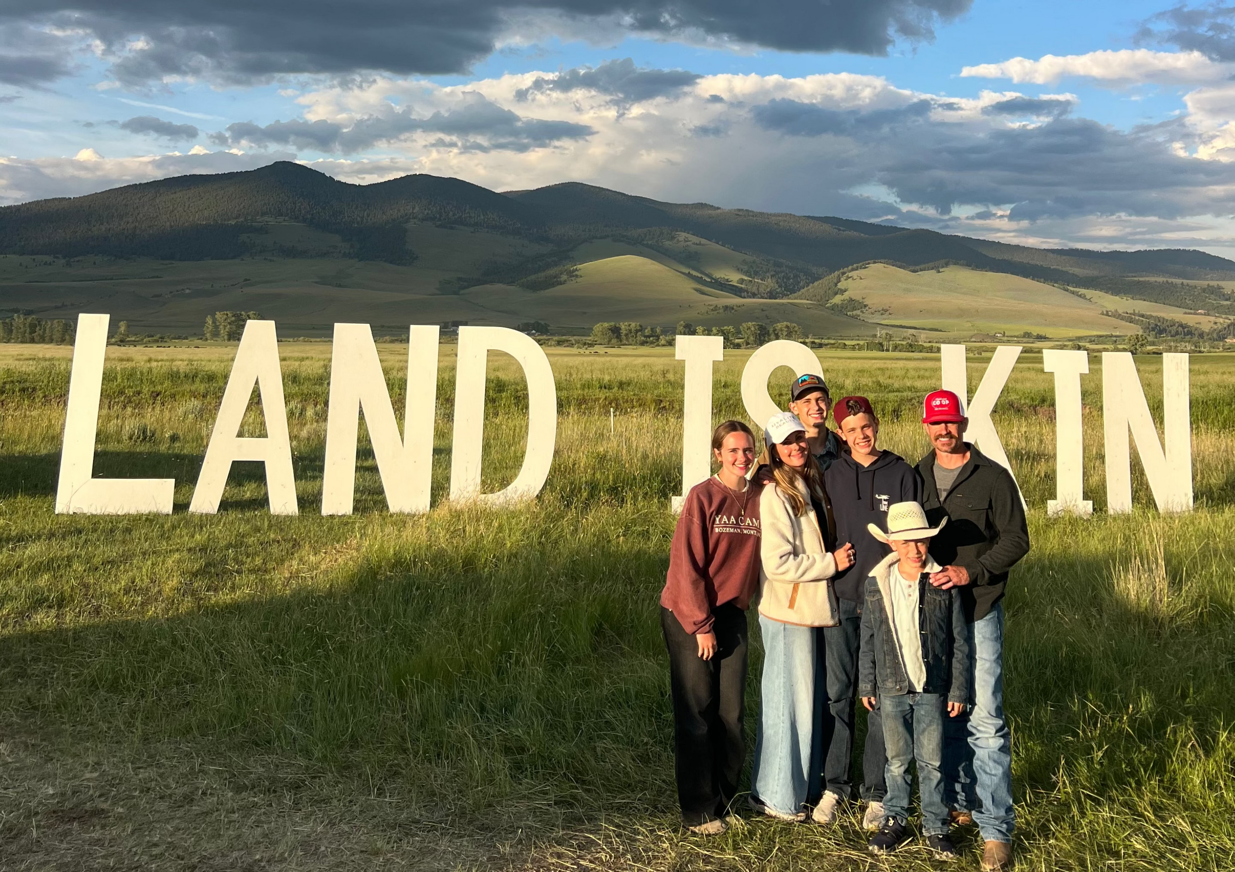 A ranch family at Old Salt Co-op in Helena, Montana, in front of a Land Is Kin sign